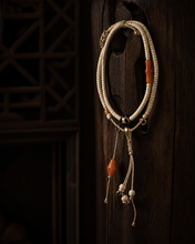 Load image into Gallery viewer, A Quiet Return beaded bracelet with pale beads and warm orange accent — image 02