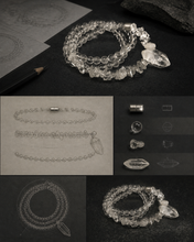Load image into Gallery viewer, NORBU OBJECTS product image direction: a neck-worn line with a central pendant or focal detail; clear and translucent tones; deep highland light; a map archivist in a quiet Lhasa guesthouse; collector archive.
