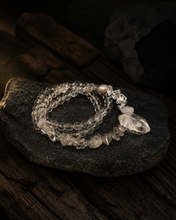 Load image into Gallery viewer, NORBU OBJECTS product image direction: a neck-worn line with a central pendant or focal detail; clear and translucent tones; deep highland light; a map archivist in a quiet Lhasa guesthouse; collector archive.
